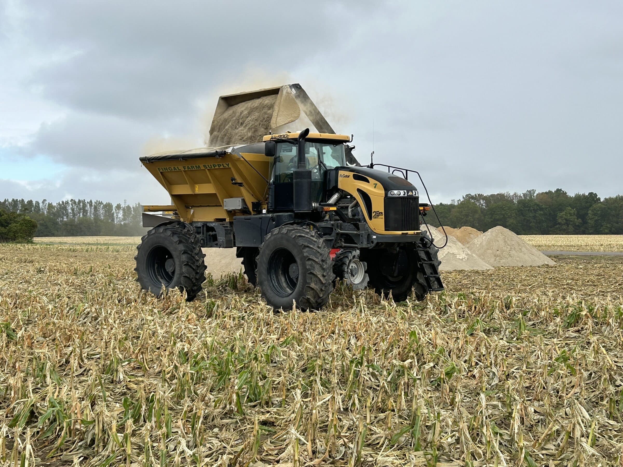 Floater spreader being filled with N-Rich fertilizer, bulk product pile staged in the background